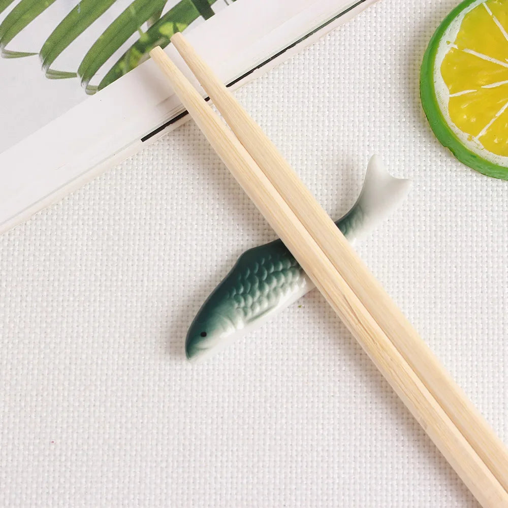 Wooden kawaii chopstick holders with a fish-shaped holder on a white surface.