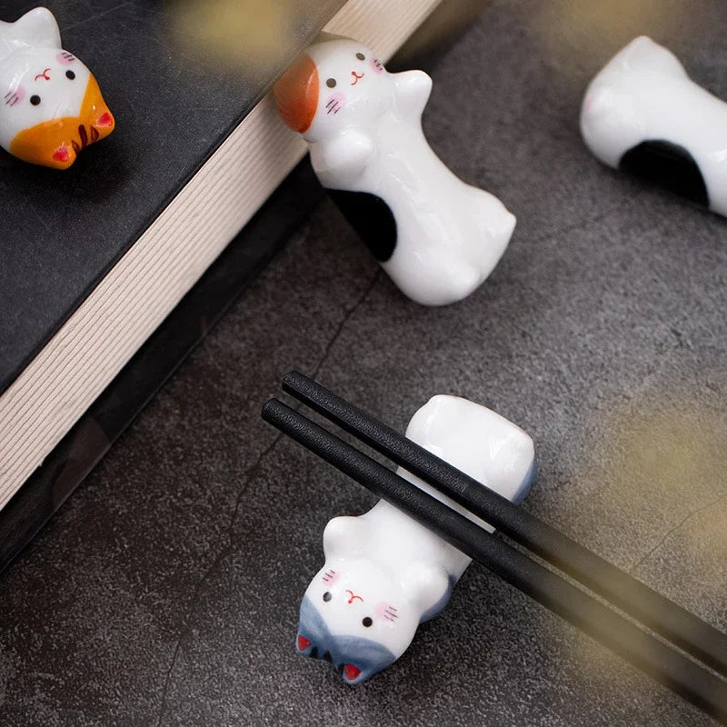 Cute animal-shaped kawaii chopstick holders on a textured surface with a book in the background.