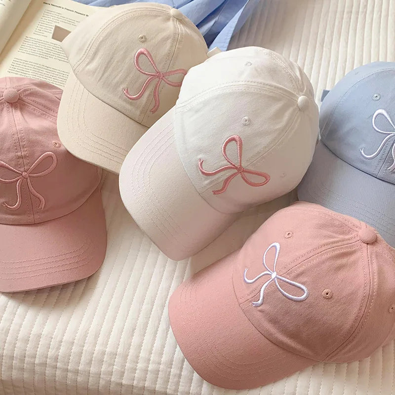 Collection of Kawaii baseball caps with embroidered bows on a textured surface