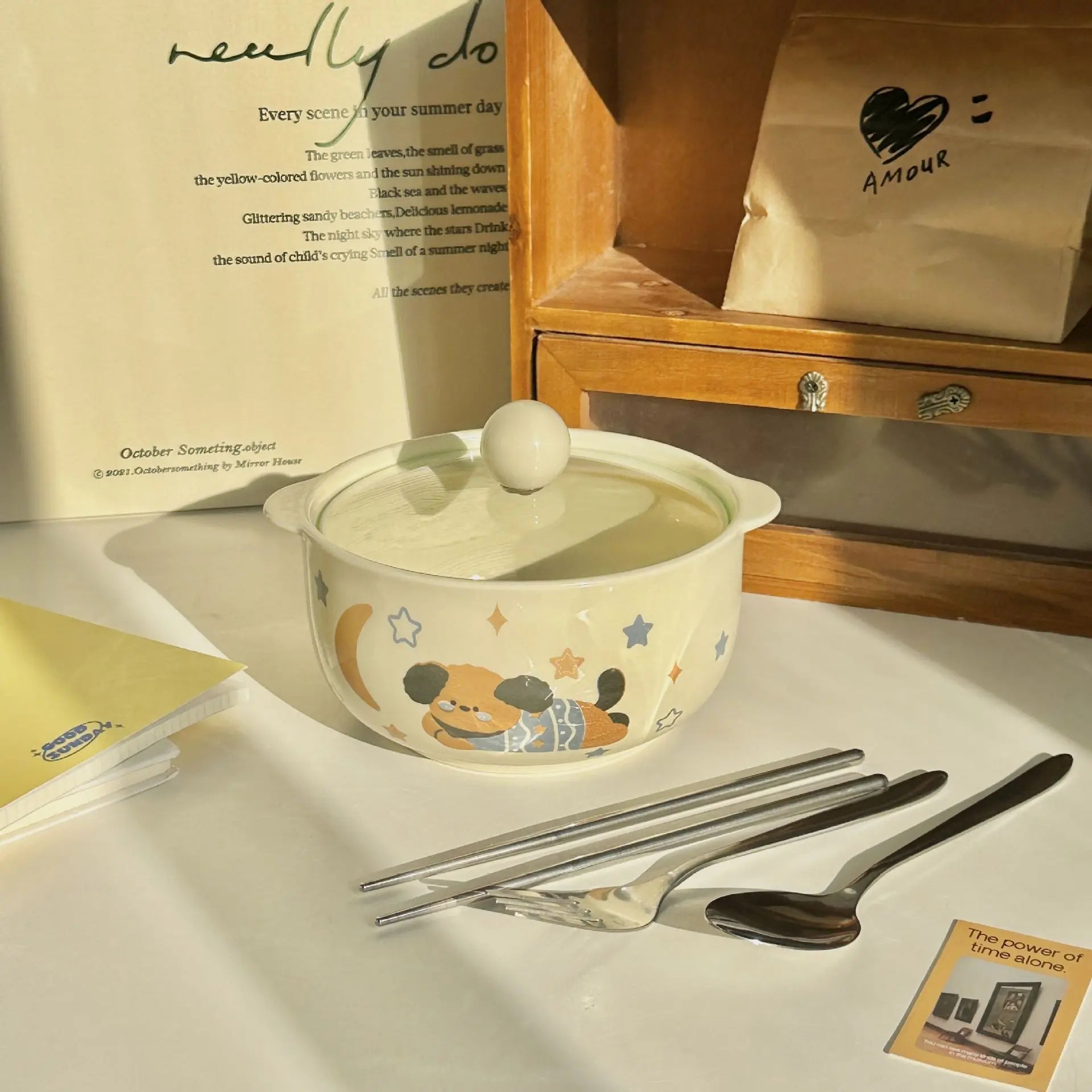 Ceramic kawaii ramen bowl with cartoon design on a table with cutlery and a book in the background