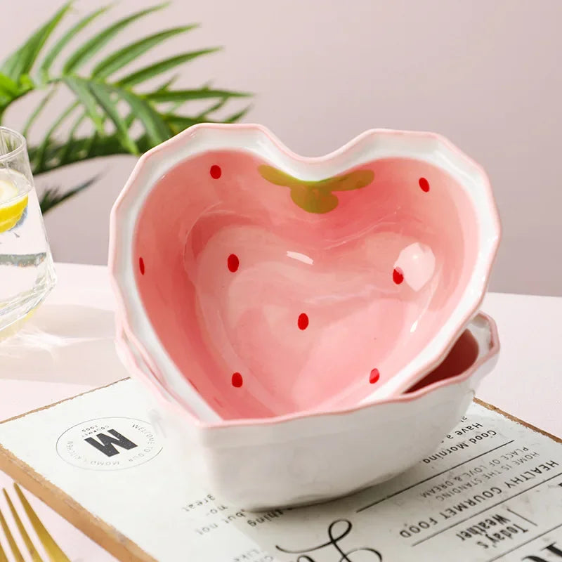 A strawberry heart shaed kawaii bowl sitting on a table