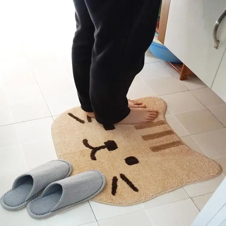 Person stepping onto a cartoon cat kawaii rug with gray slippers nearby on a tiled floor.