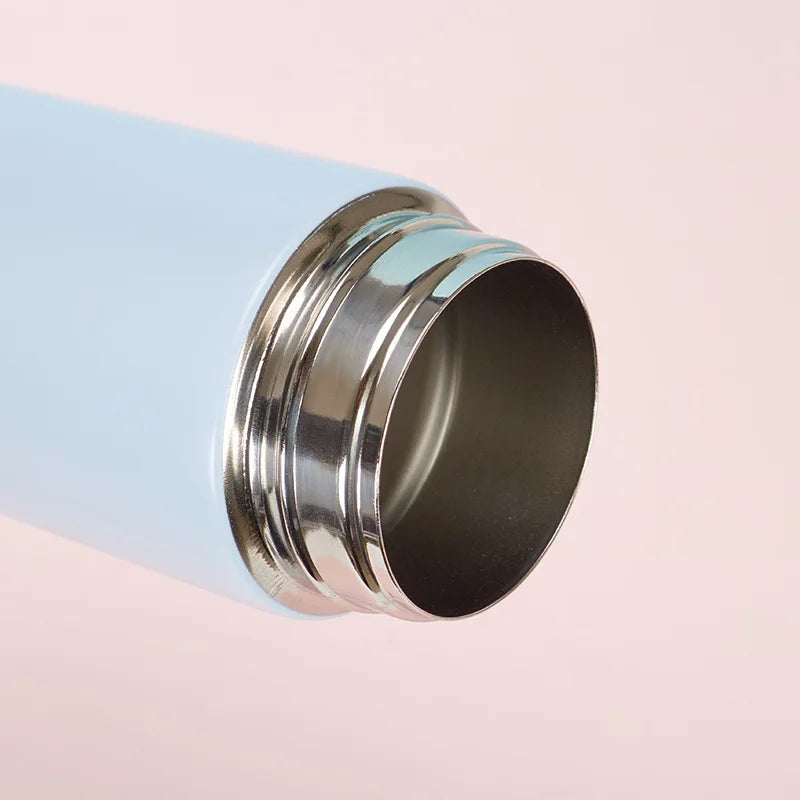 Close-up of a metal kawaii water bottle with a light blue exterior on a pink background