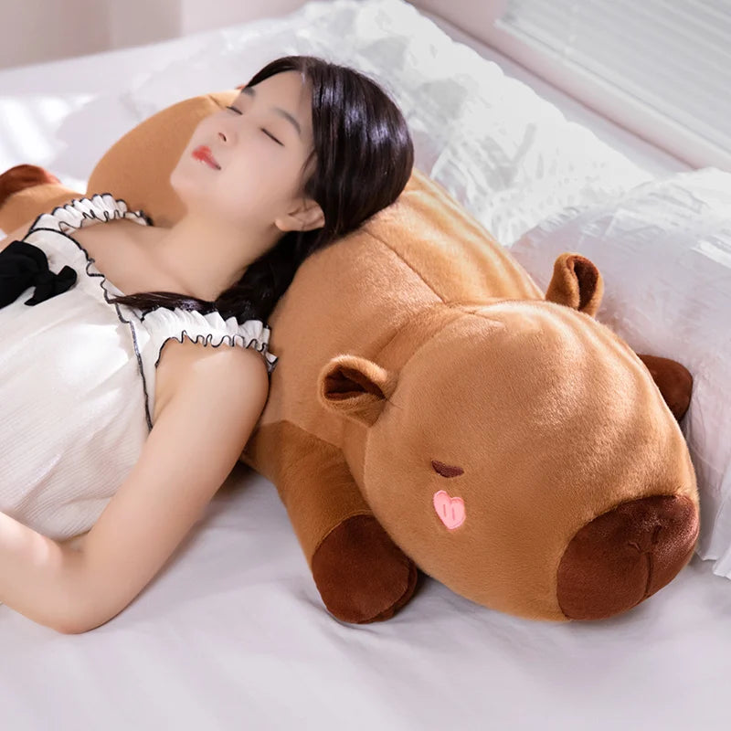 Woman lying on a bed with a large brown dog-shaped kawaii pillow.