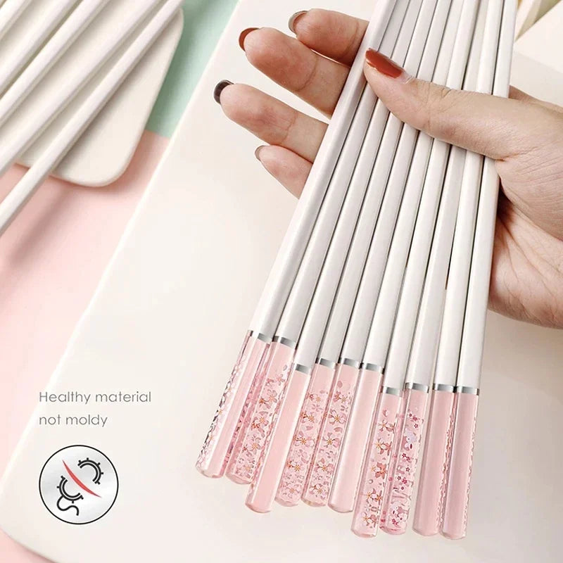 Hand holding a set of pink and silver kawaii chopsticks with a close-up of the tips.