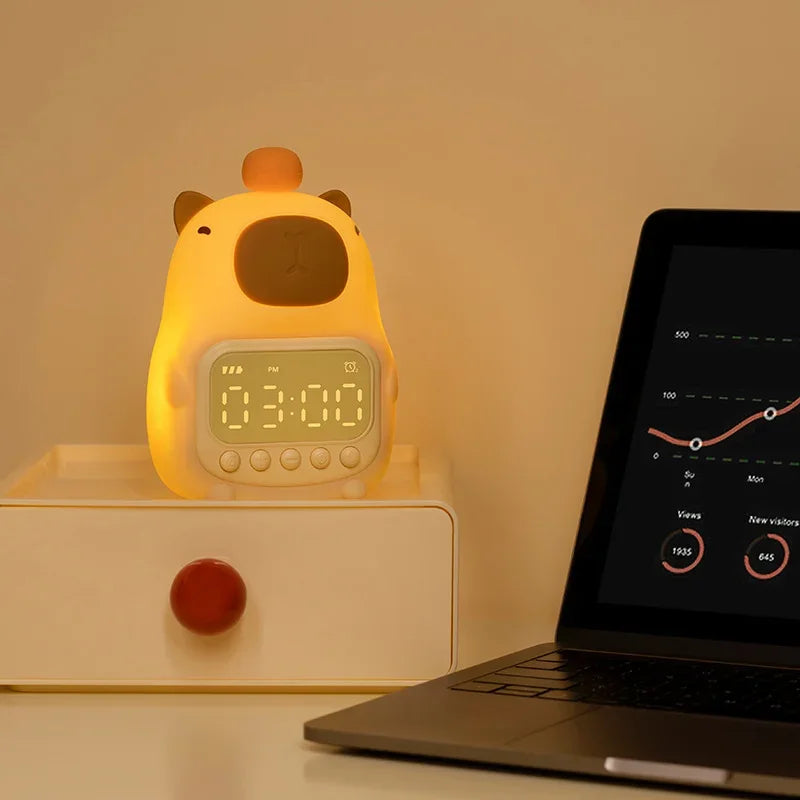 Yellow cartoon-style kawaii alarm clock on a white surface with a laptop displaying a graph in the background.