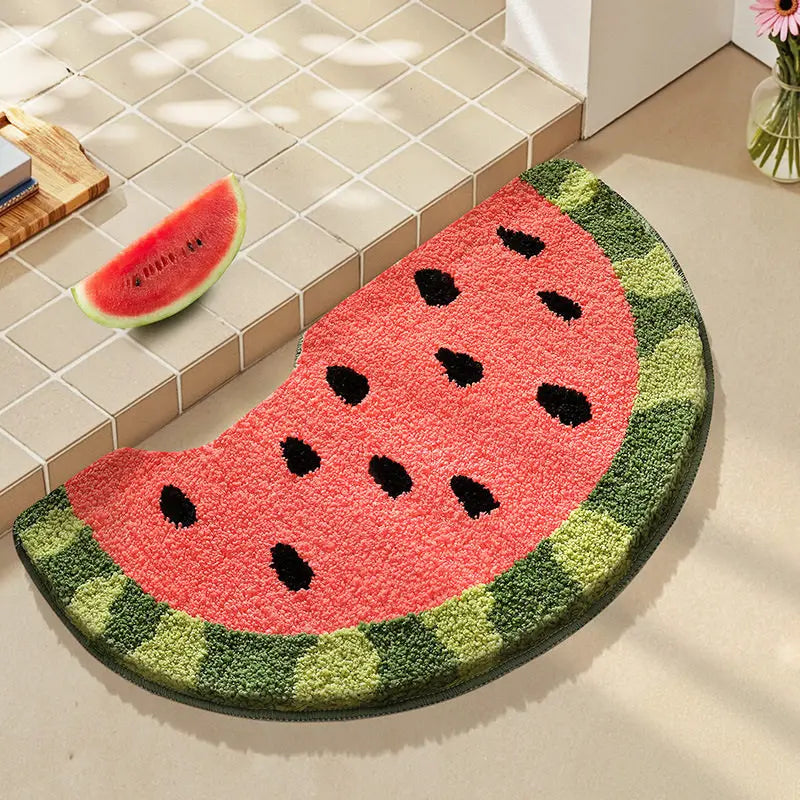 Watermelon-shaped kawaii doormat on a tiled floor with a slice of watermelon and a vase in the background.