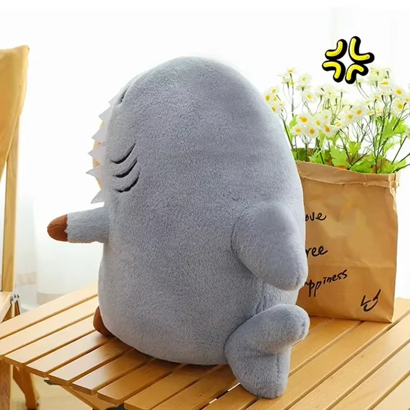 Gray kawaii plush shark toy on a wooden surface with a bag of flowers in the background