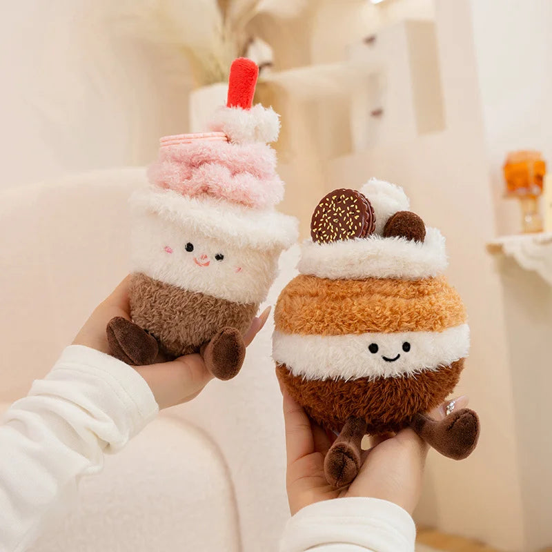 Two kawaii plush toys resembling ice cream cones held by a person against a neutral background.