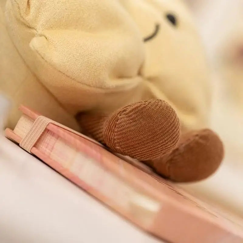 Kawaii plush toy bear lying on a pink book with a blurred background