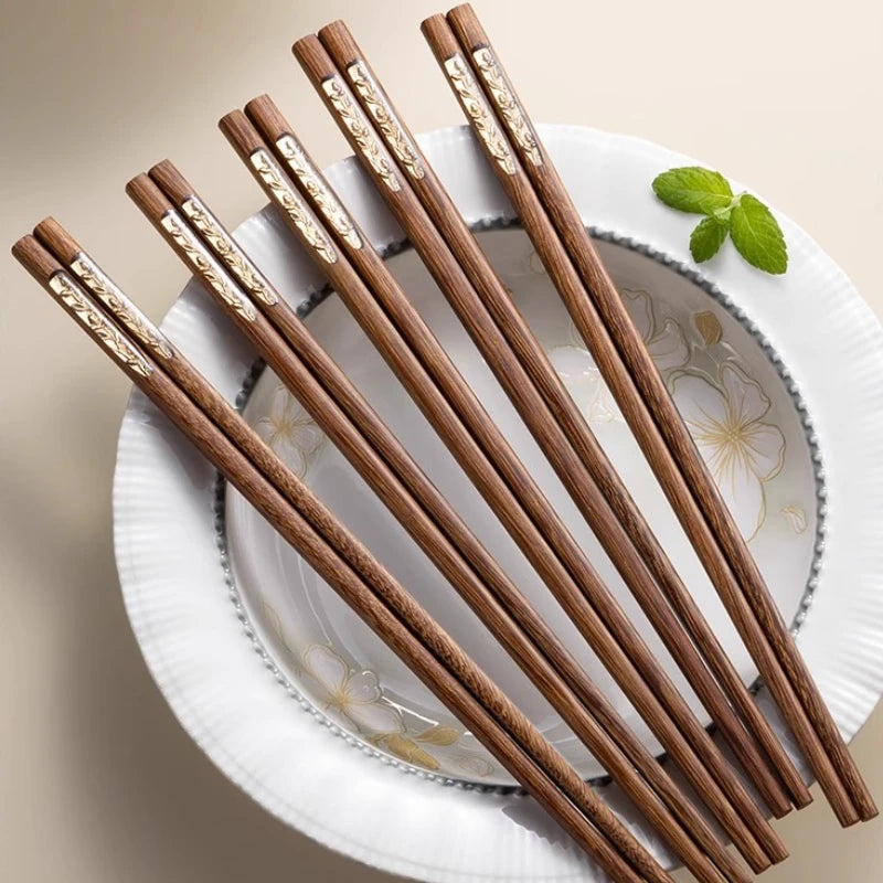 Set of wooden kawaii chopsticks with gold accents on a decorative plate.