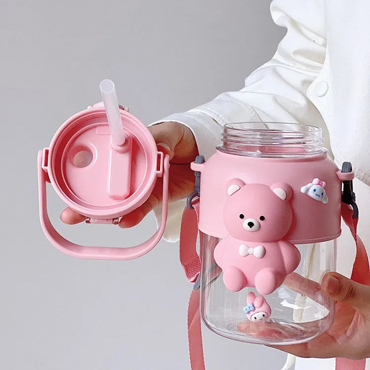 Pink kawaii water bottle with bear design held by a person, on a gray background.