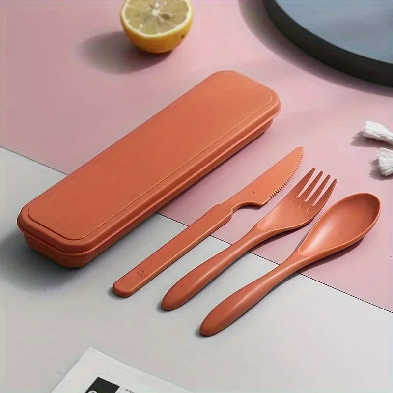 Set of orange kawaii utensils including knife, fork, and spoon with a carrying case on a pink surface.