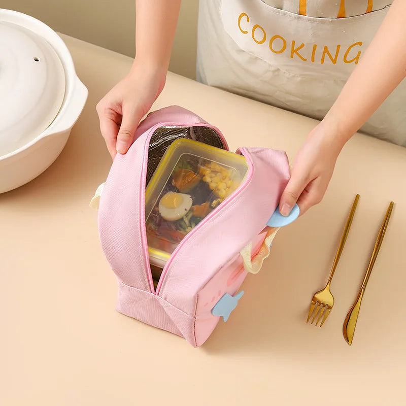 Person opening a pink kawaii lunch bag containing a bento box with food on a beige surface.