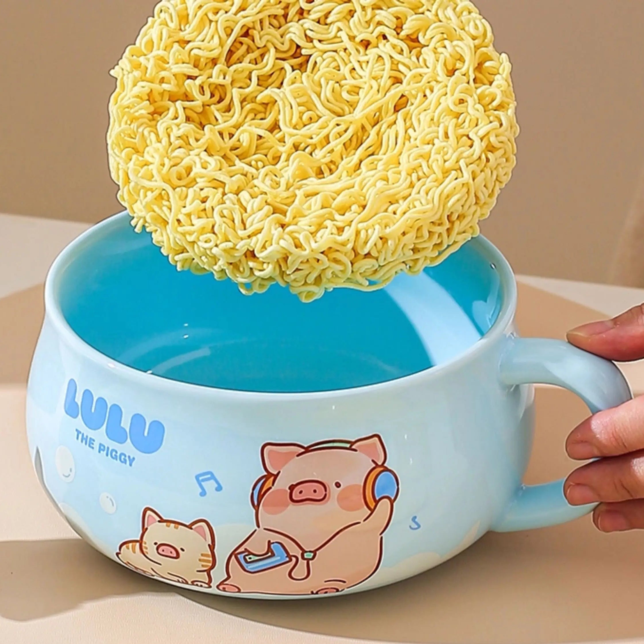 Blue kawaii ramen bowl with cartoon design holding a yellow sponge and ramen noodles on a beige background