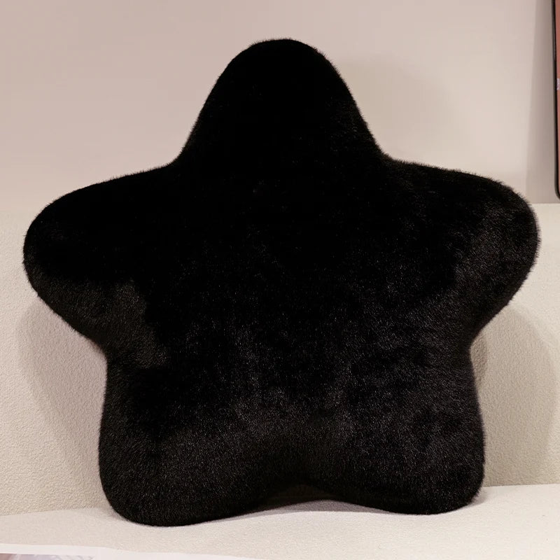 Black star-shaped pillow on a light-colored surface with a neutral background