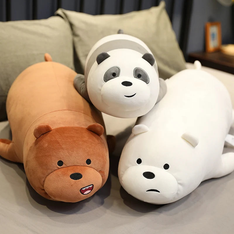 Three kawaii plush toys shaped like a bear, panda, and seal on a bed.
