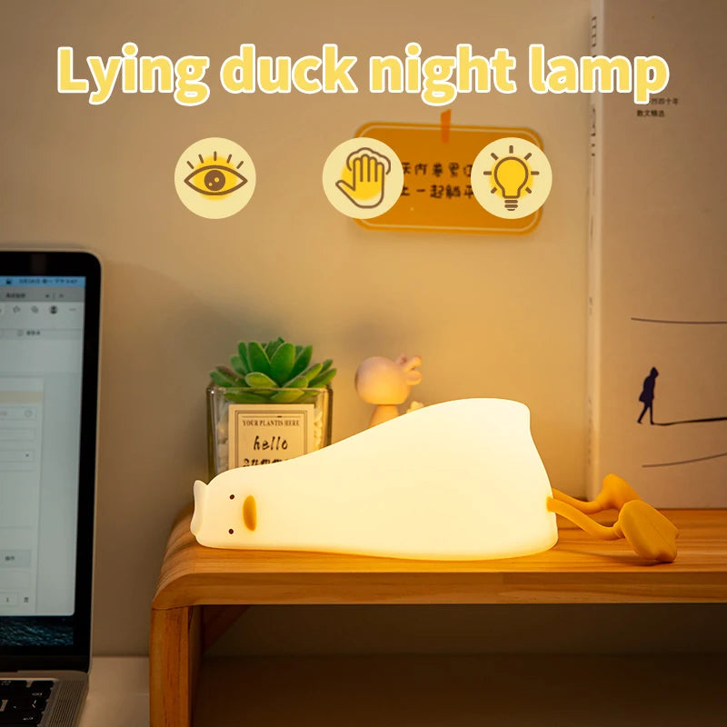 Lying duck kawaii night lamp on a desk with a laptop and plant in the background