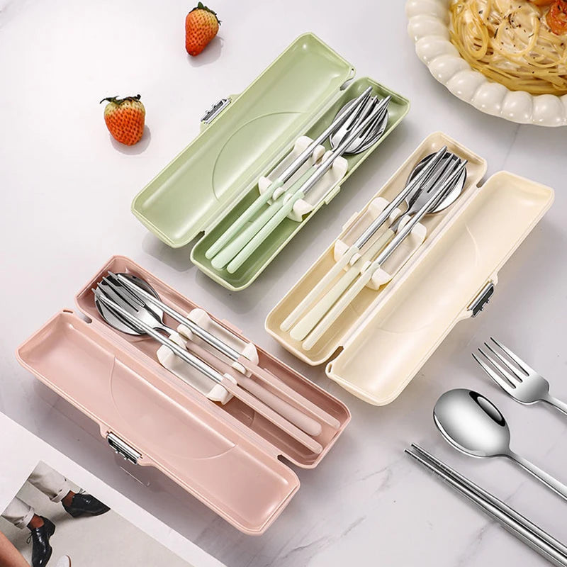 Set of silver kawaii utensils in colorful cases on a marble surface with strawberries and pasta.