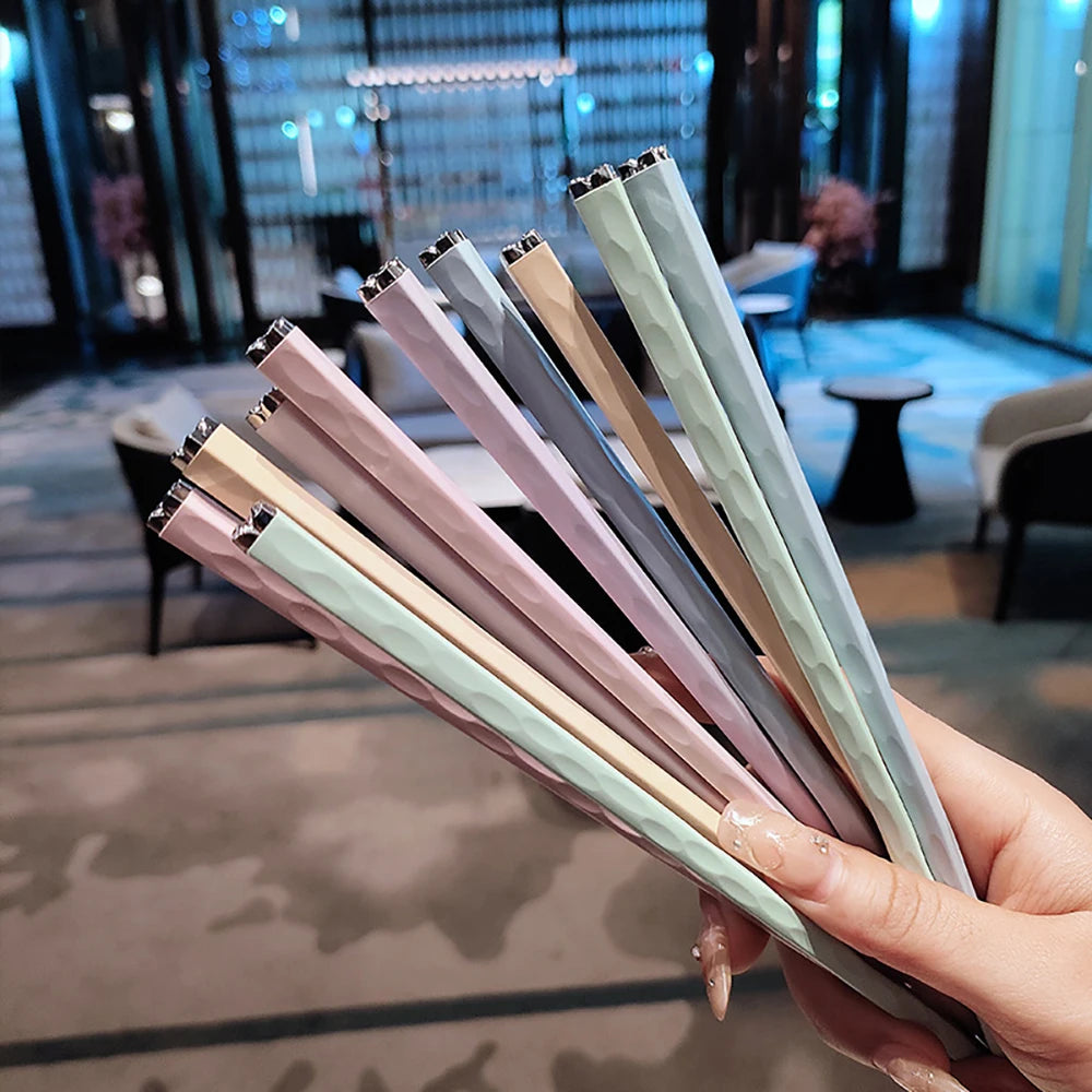 Hand holding a set of kawaii chopsticks with a blurred indoor background