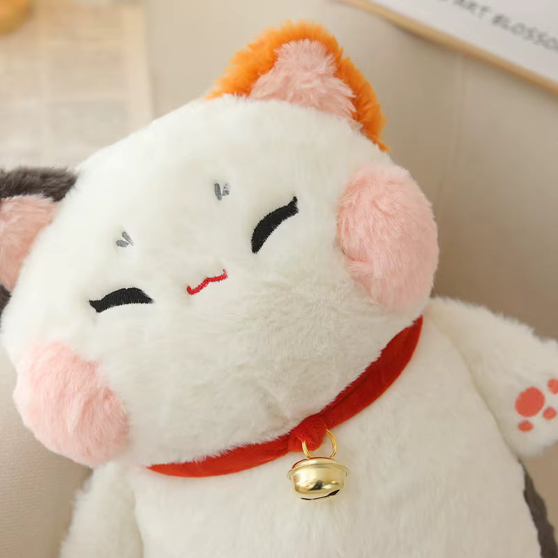 Plush toy cat with a bell around its neck on a neutral background