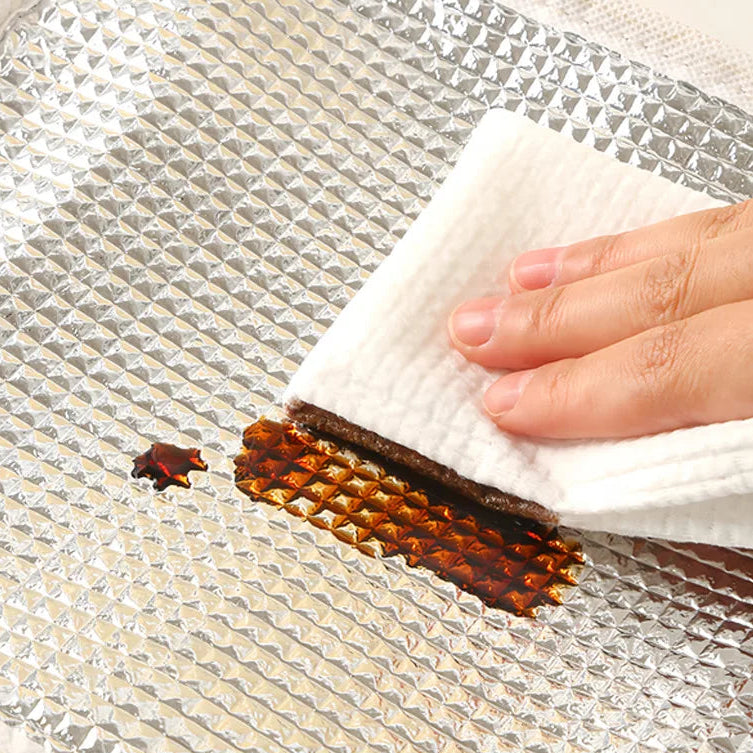 Hand using a white cloth to wipe up a spill on a reflective surface of a kawaii lunch bag