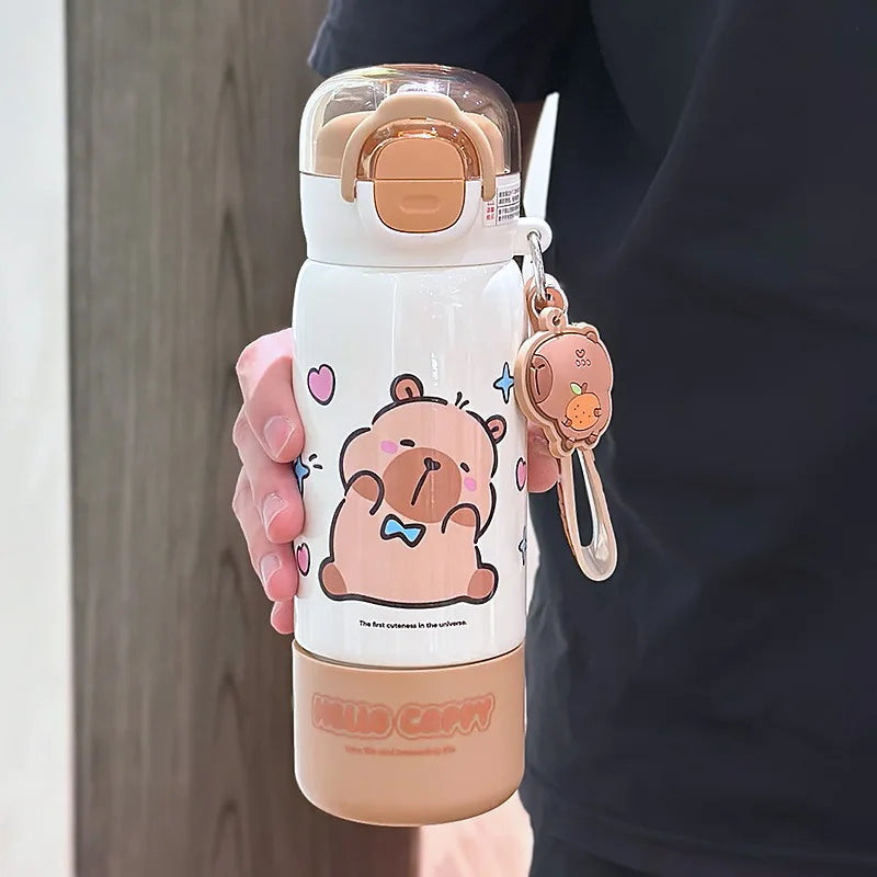 Person holding a cute kawaii water bottle with cartoon design and matching keychain.