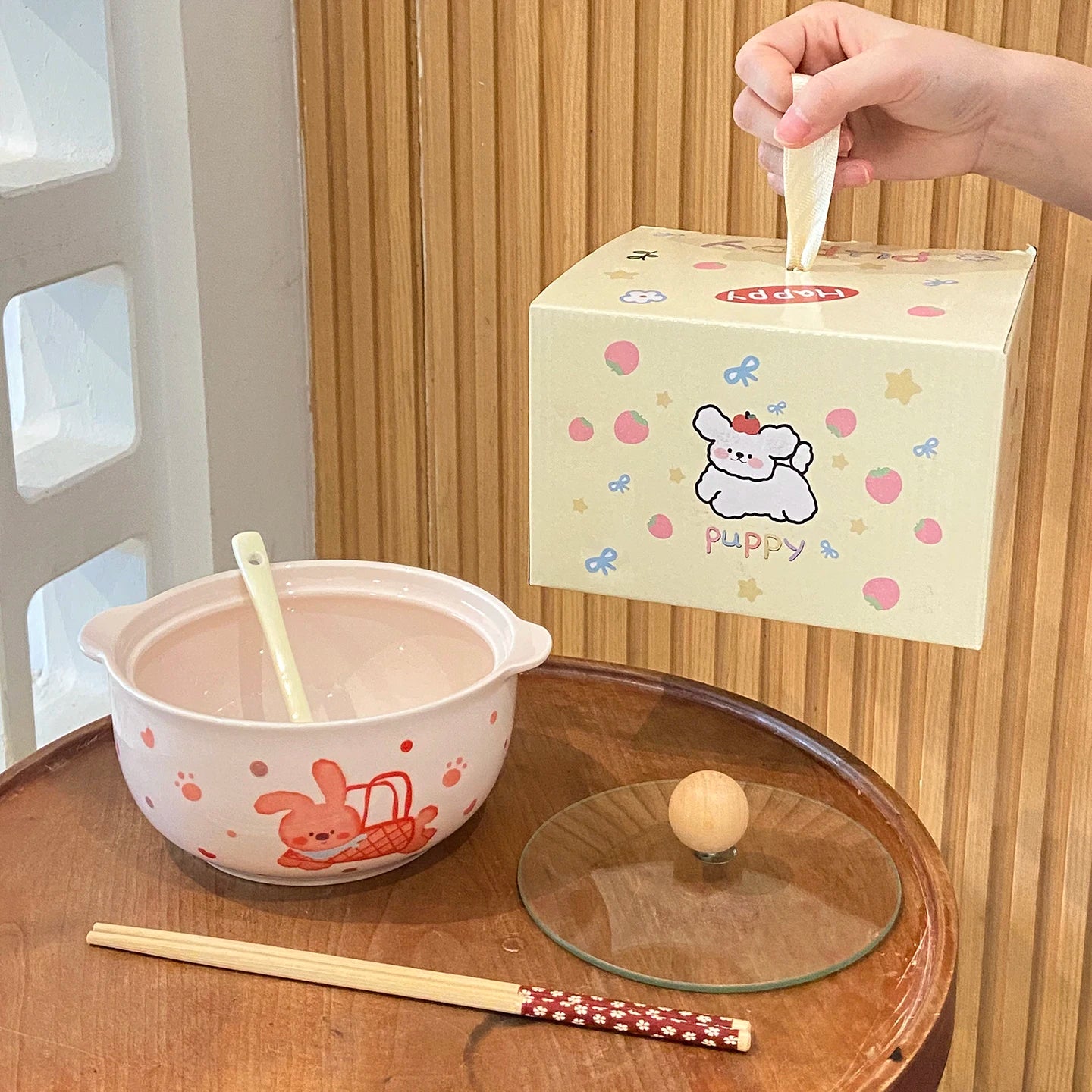 Cute cartoon-themed box with a kawaii ramen bowl, spoon, and chopsticks on a wooden surface.