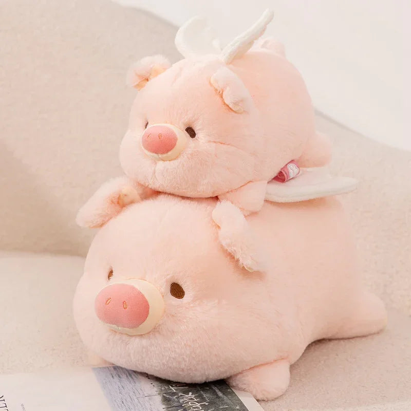 Two pink kawaii plush toys, one resembling a pig and the other a unicorn, on a light surface.