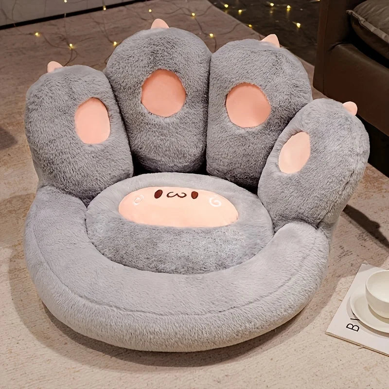 Gray paw-shaped kawaii cushion with pink pads on a beige carpet