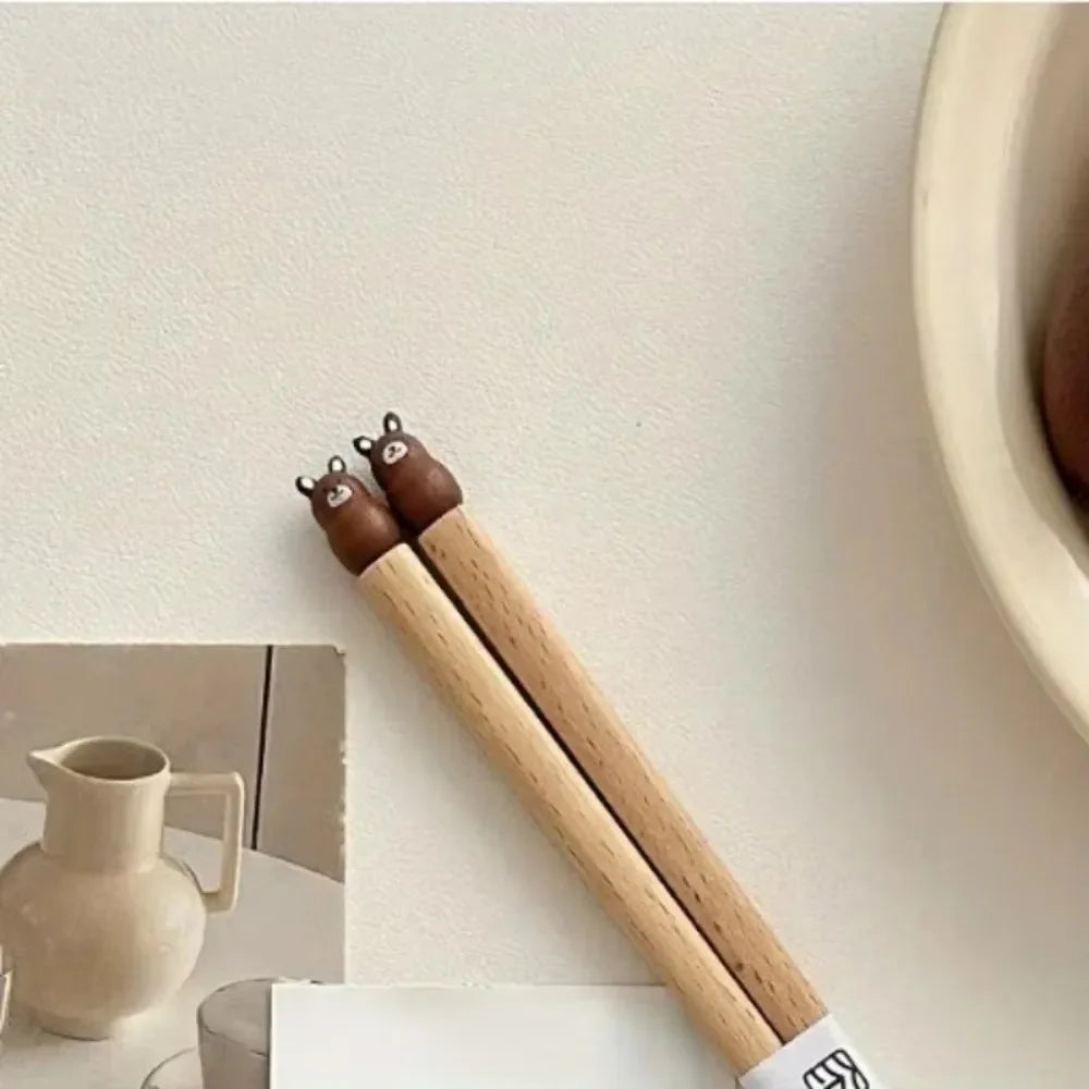 Wooden kawaii chopsticks with bear-shaped ends on a light surface