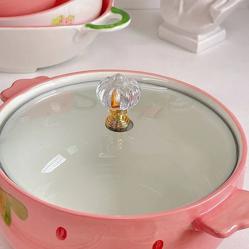 Pink kawaii bowl with a glass lid featuring a decorative handle on a white surface.