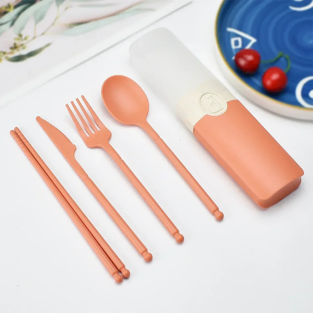 Set of peach-colored kawaii utensils with a carrying case on a light surface.