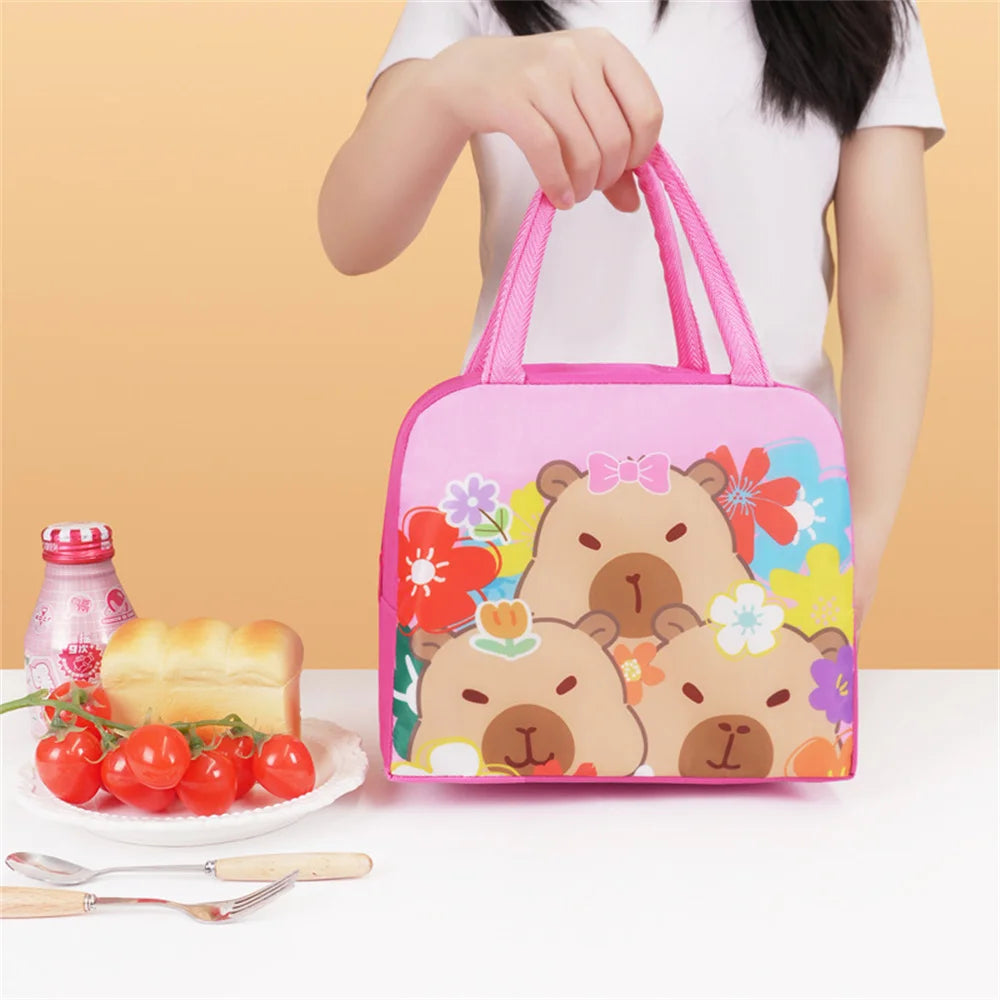 Person holding a pink kawaii lunch bag with bear design, next to a plate of food on a yellow background