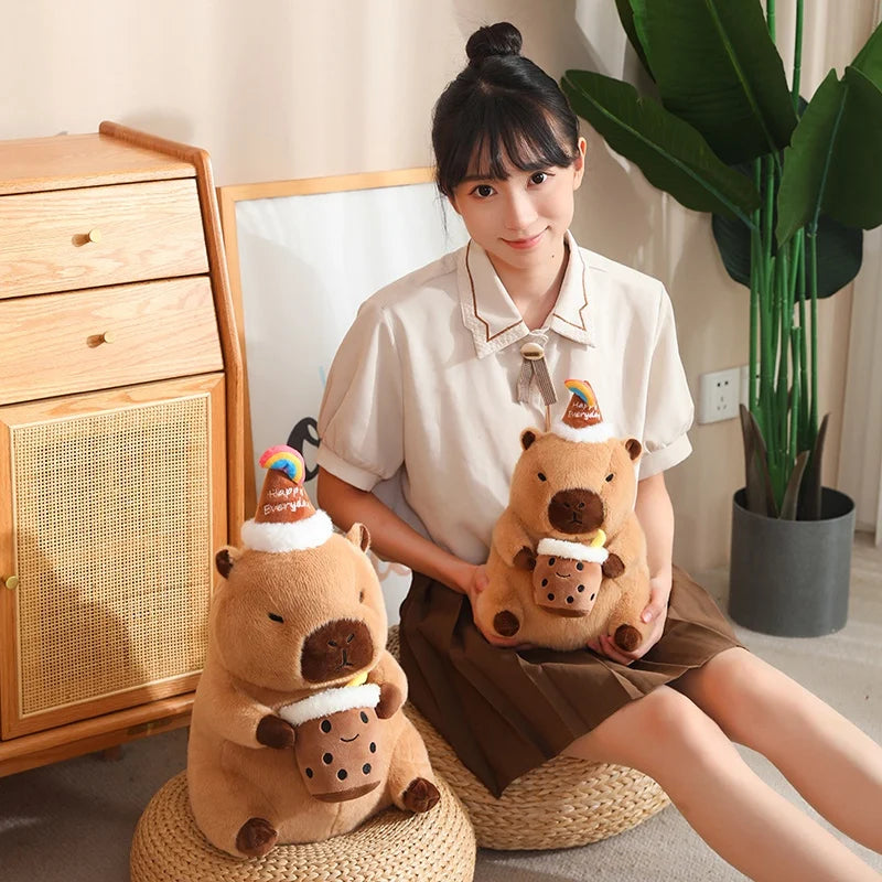 Person holding two capybara plush toys resembling beavers in a room with a wooden cabinet and plant.