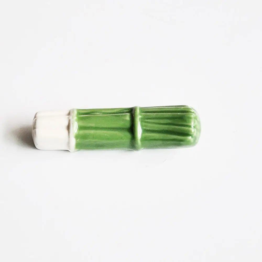 Green and white cylindrical kawaii chopstick holders on a white background